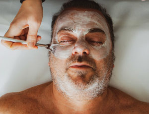 Middle-aged man in a spa with a facial mask.